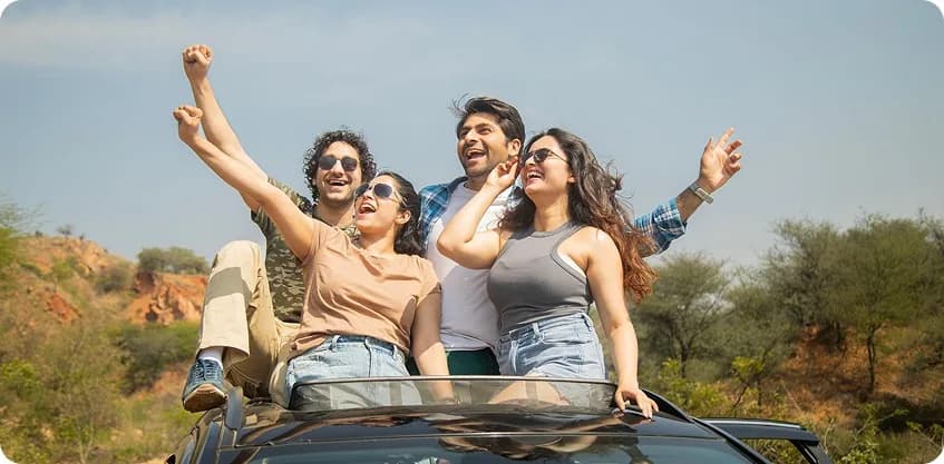 Friends celebrating on a self-drive SUV sunroof during a Friendship Day road trip