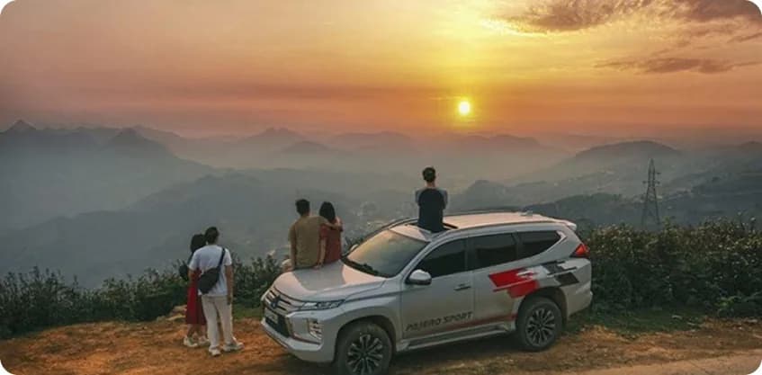 Friends watching sunrise from a mountain overlook with a self-drive SUV