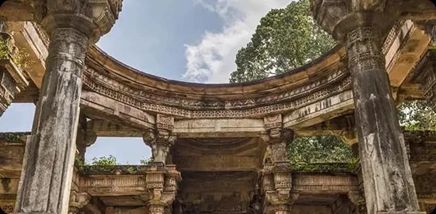Ancient carved stone temple ruins looking up through a circular opening in Polo Forest