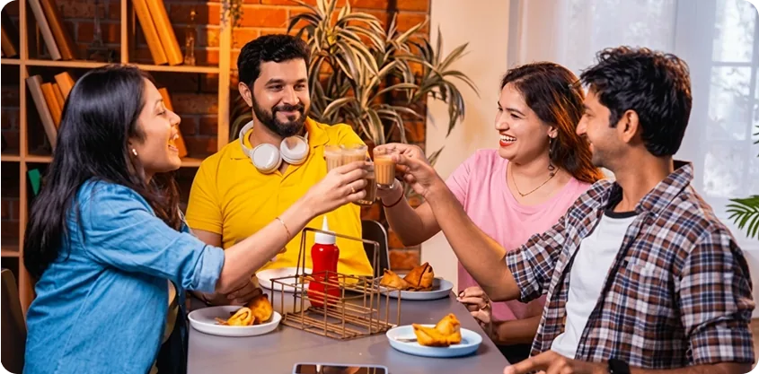 Siblings and friends toasting chai over samosas at a cafe