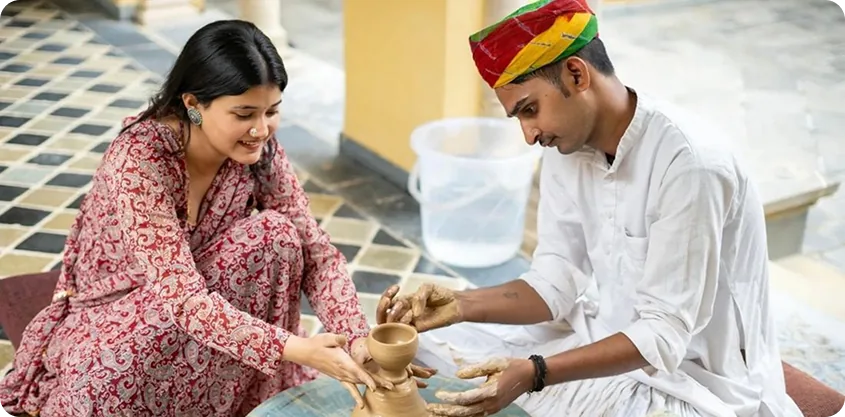 Siblings trying pottery together on a traditional wheel